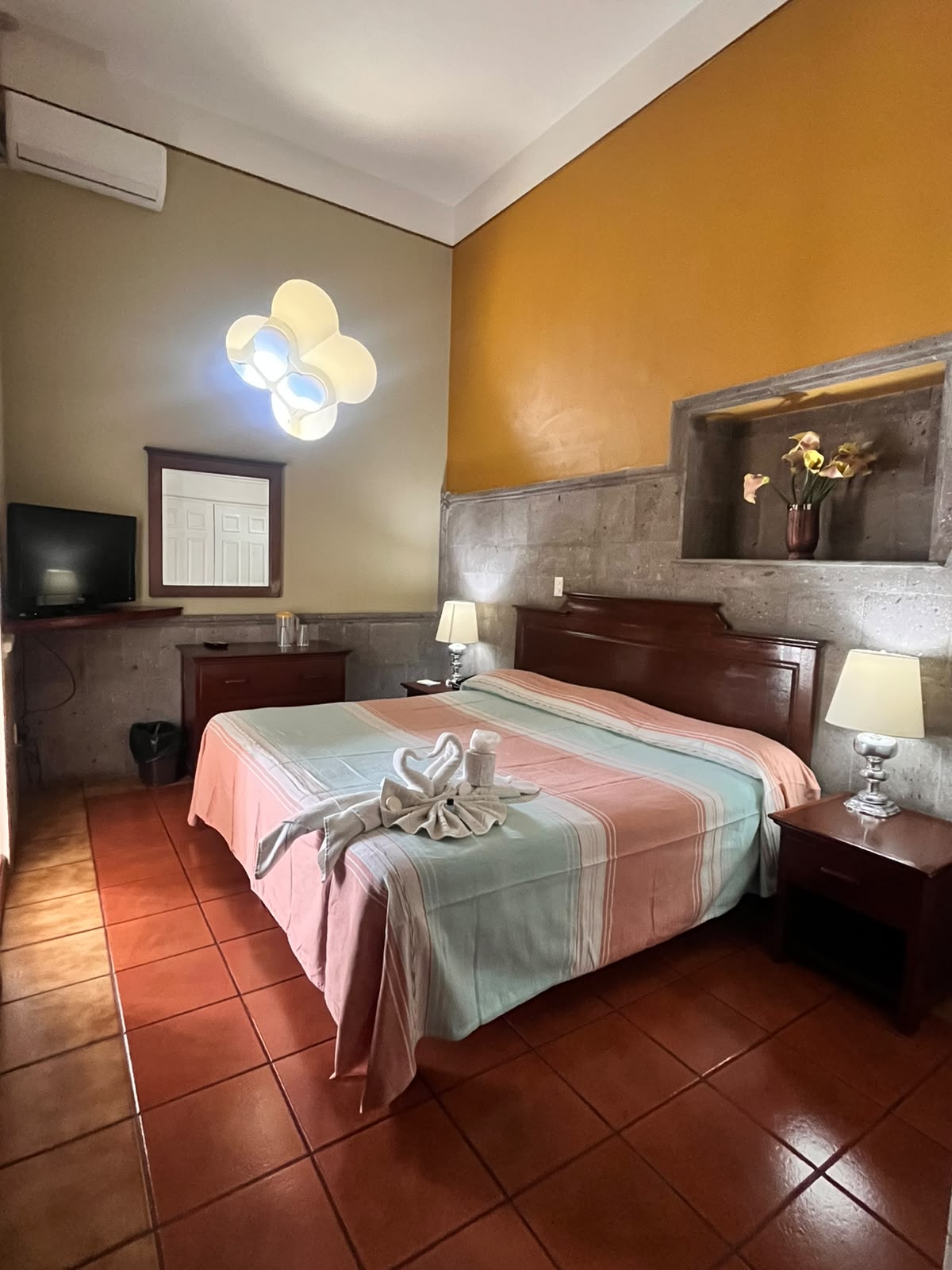 Habitación sencilla con muro naranja y cama matrimonial