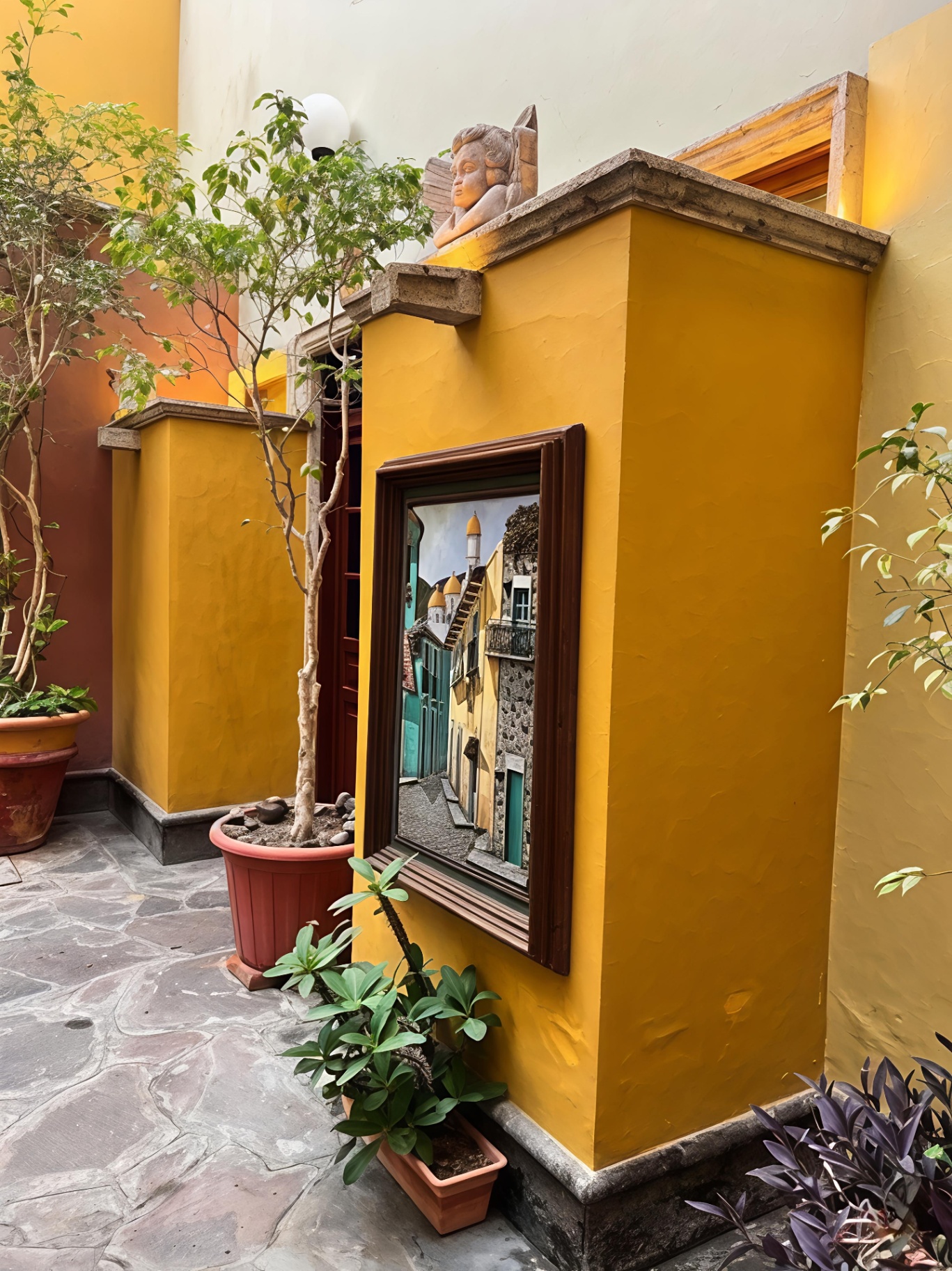 Querubín de cantera y cuadro en muro amarillo